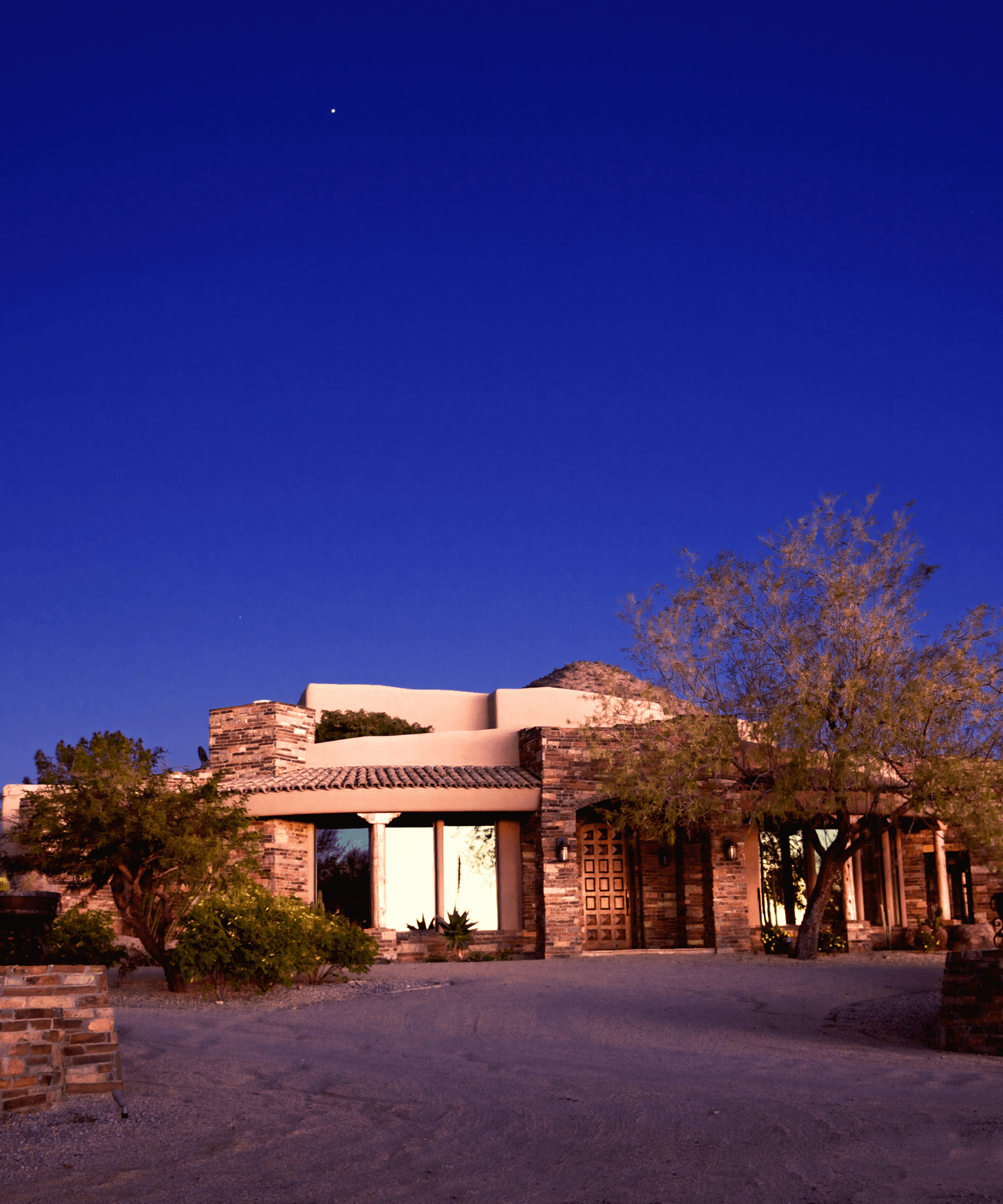 A West Valley adobe home at dusk, warmly lit against a deep blue desert sky.